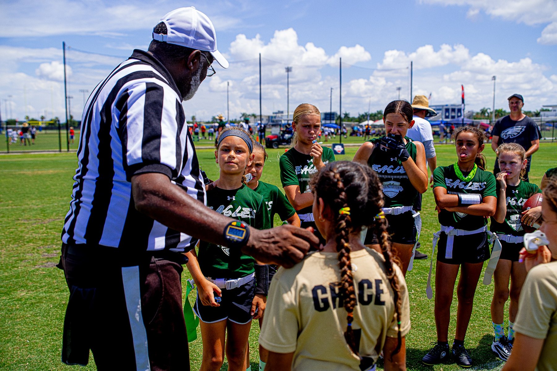 Girls flag football referee and team huddle